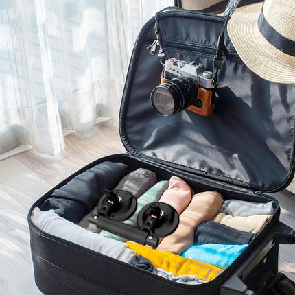 Open suitcase with camera, shoes, and clothes on a light background