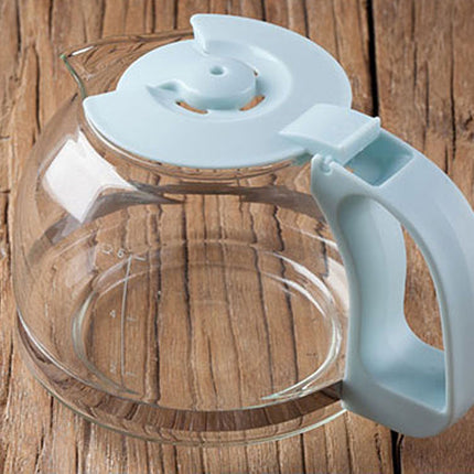 A clear glass coffee pot with a light blue plastic handle, lid, and spout, shown on a rustic wooden surface.
