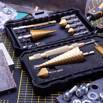 A black metal drill bit set organized in an open hard case, surrounded by hardware tools and a cutting mat on a workbench.