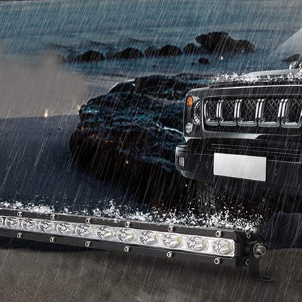 Black SUV with a large LED light bar on a rainy road