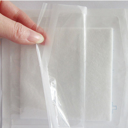 Hand holding clear plastic wrap against a white background