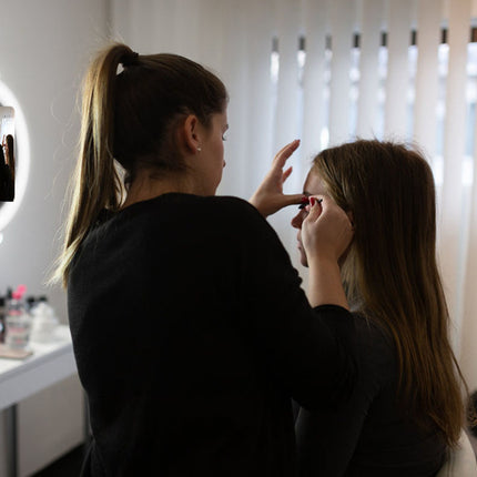 Makeup artist applying makeup to a model in a professional setting.