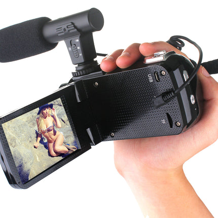 Hand holding a video camera with a microphone attached, displaying a screen on a white background.