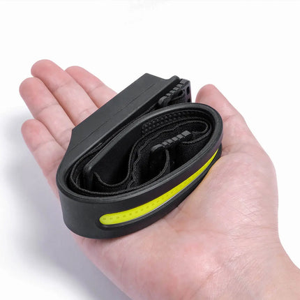Black and yellow bike inner tube held in a hand against a white background
