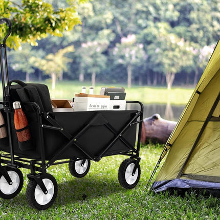 Black folding wagon with supplies next to a tent in a camping setting