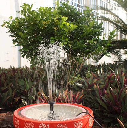 Small water fountain with plants and building in the background