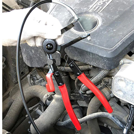 Red pliers being used on a car engine