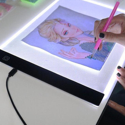 Person using a digital drawing tablet with a light-up screen displaying an illustration.