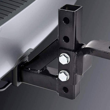 Close-up of a black metal hitch receiver mount attached to a silver vehicle body, with two silver bolts visible against a dark gray background.