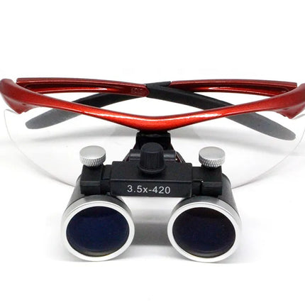 Magnifying loupes with a red and black headband, clear protective eyeglass lenses, and two eyepieces with silver metal rims and blue-tinted lenses, shown on a white background.