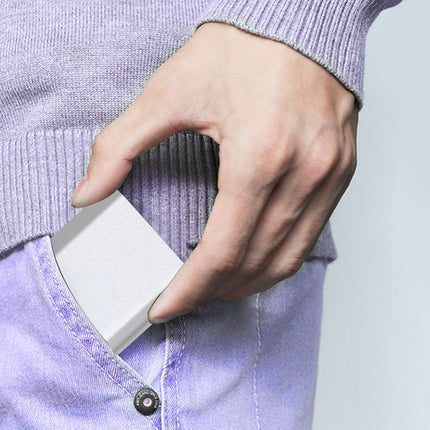 Hand holding a small white device against a blurred background