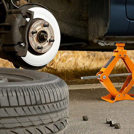 Car tire being changed with a jack and brake rotor visible