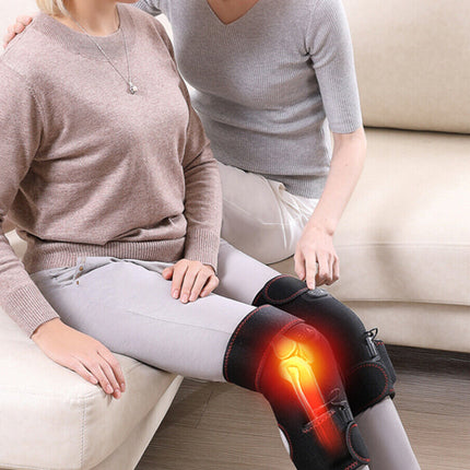 Two people sitting on a couch with one person wearing a knee brace illuminated by a red light.