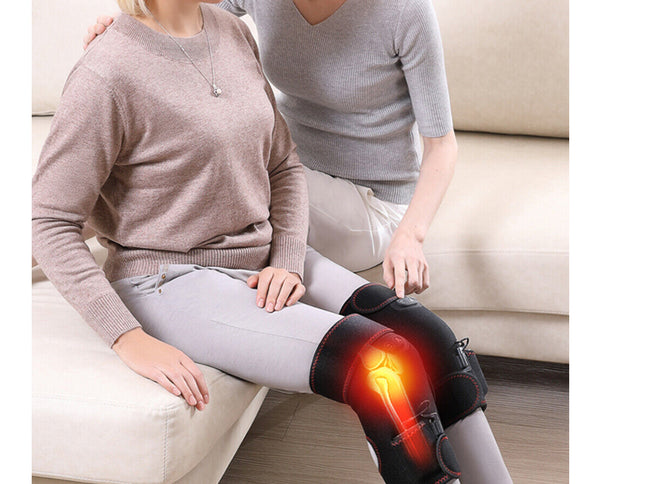Two people sitting on a couch with one person wearing a knee brace illuminated by a red light.
