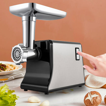 Handheld meat grinder on a kitchen counter with a hand pressing a button.