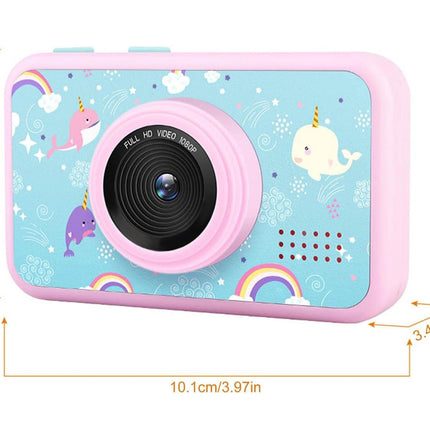 Pink children's camera with a light blue printed back featuring cartoon unicorns, rainbows, clouds, and stars, shown with dimension lines indicating its size.
