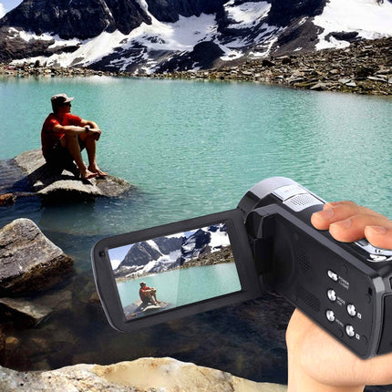 Person taking a photo of a scenic lake with mountains using a digital camera.