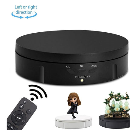 Black round device with remote control and small figurines on a white background