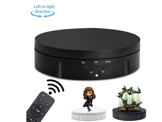 Black round device with remote control and small figurines on a white background
