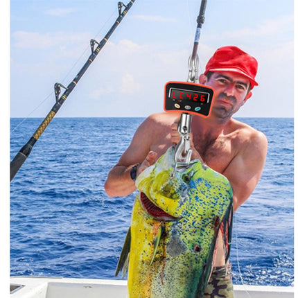 Man holding a large fish caught on a fishing line with a digital display, ocean in the background