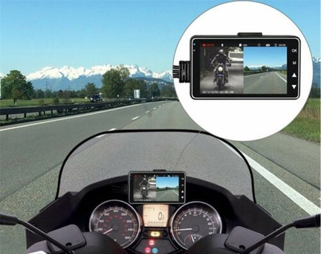 Motorcycle dashboard with a mounted camera showing a rider on a road with mountains in the background.