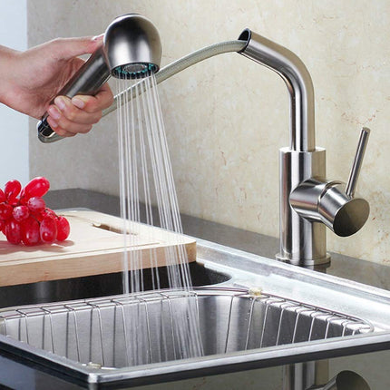 Person using a handheld showerhead to rinse dishes under a kitchen faucet.