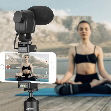 Person practicing yoga with a smartphone camera setup on a rooftop.