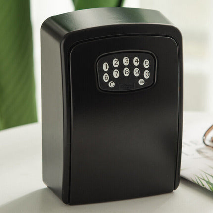 Black electronic key safe on a white surface with a blurred green plant in the background