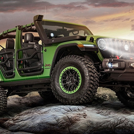 Green Jeep Wrangler on rocky terrain with a sunset sky