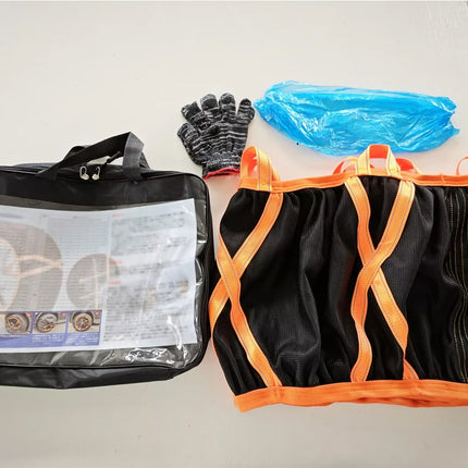 A black heavy-duty lifting sling with bright orange webbing straps, shown alongside its black carrying bag containing an instruction manual, a pair of black and gray work gloves, and a blue plastic bag, all laid out on a light gray floor.