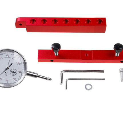 A precision dial indicator kit with a silver analog dial, red metal adjustment blocks, silver hex keys, and mounting screws on a white background.
