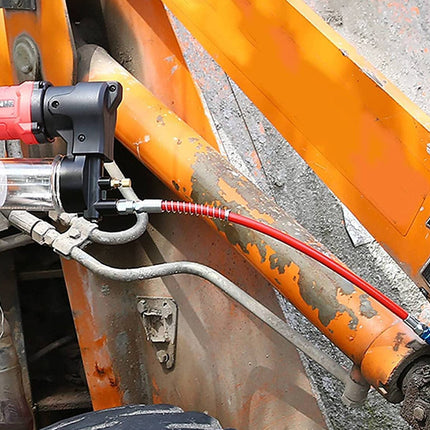 Red and black tool attached to a large orange machine on a construction site.