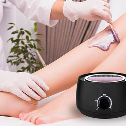 Person getting a hair removal treatment on their leg with a black wax warmer.