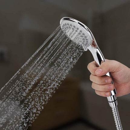 Hand holding a shower head with water flowing, against a dark background