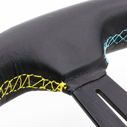 Close-up of a black leather steering wheel rim with contrast stitching, featuring bright yellow stitching on one side and light blue stitching on the other, with a black metal center column visible against a white background.