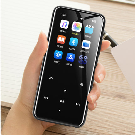 A hand holding a black tablet-style smartphone with a glossy screen displaying app icons, set against a light wood tabletop background.