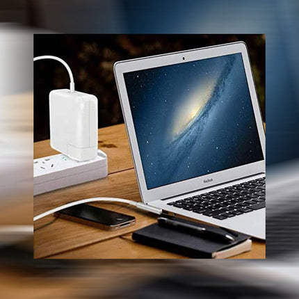 Laptop, smartphone, and power adapter on a wooden surface with a blurred background