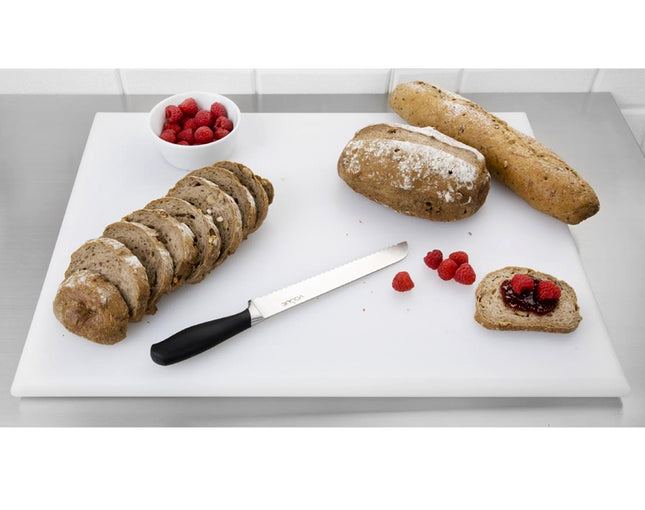 Loaves of bread, a knife, and raspberries on a white cutting board.