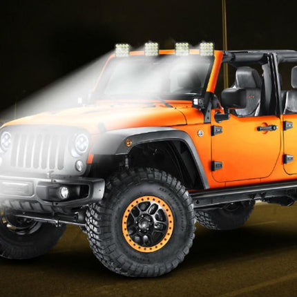 Orange off-road vehicle with headlights on, highlighting its rugged design.