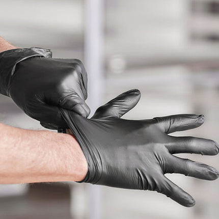 Person putting on a black glove with a blurred background
