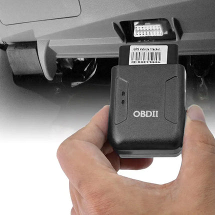 A hand holding a black OBDII Off Vehicle Tester device in front of a car dashboard connector port.