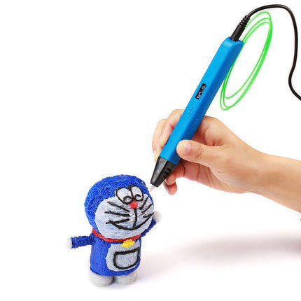 A hand holding a blue 3D printing pen with a green coiled filament, creating a small blue Doraemon plush toy on a white background.