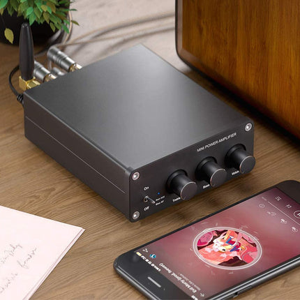 Audio power amplifier with smartphone displaying music app on a wooden surface