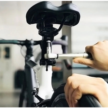 Person adjusting a bicycle seat with a tool, blurred background