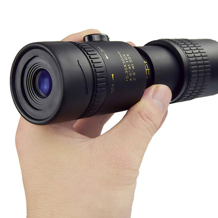 Hand holding a black monocular telescope on a white background