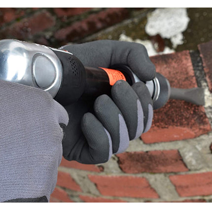 Person wearing gray gloves holding a tool on a brick surface