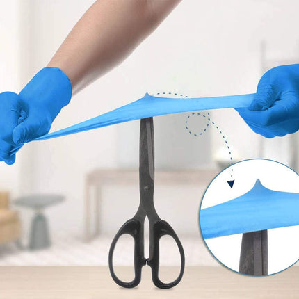 Person wearing blue gloves stretching a blue strip of material with scissors in the background
