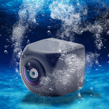 A dark gray underwater camera with a rounded cube shape and a visible front lens, shown floating in blue water with bubbles around it.