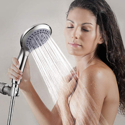 Woman holding a shower head with water flowing, against a neutral background