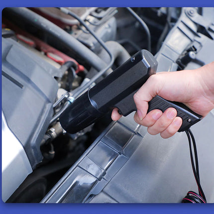Hand holding a diagnostic tool near a car engine